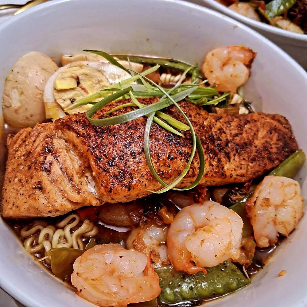 Salmon and shrimp over noodles, plated